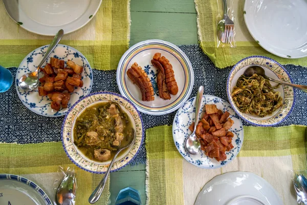 Fresh delicious local Northern Thai style food including fried and grilled pork, boiled vegetable and other dishes on green table, top view — Stock Photo, Image