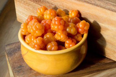 Cloudberry Rubus chamaemorus, ahşap masa üzerinde turuncu kâseye, Hemsedal kayak merkezi yakınlarındaki Norveç dağlarında hasat, Buskerud, Norveç, takvim, poster, duvar kağıdı basmak için fotoğraf