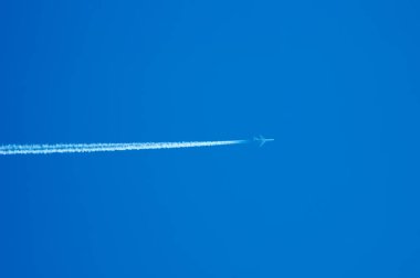 Yüksek uzun beyaz iz bırakarak masmavi gökyüzünde uçan yolcu uçağı