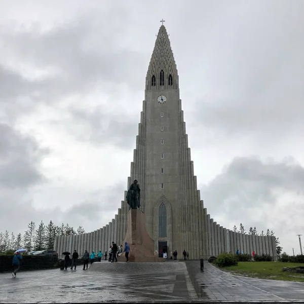 REYKJAVIK, ICELAND - June 30, 2018: Hallgrimskirkja, a Lutheran parish church with Leif Erikson stature and people on cloudy sky. Cathedral building with concrete facade. — ストック写真
