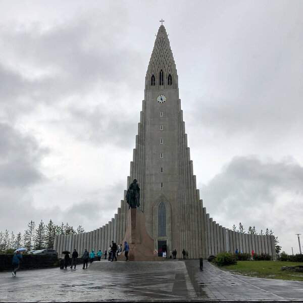 REYKJAVIK, ICELAND - June 30, 2018: Hallgrimskirkja, a Lutheran parish church with Leif Erikson stature and people on cloudy sky. Cathedral building with concrete facade.