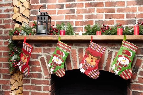 Calcetines de Santa Navidad bellamente decorados colgando de una chimenea en la pared de ladrillo esperando regalos, vista de cerca Imagen de archivo