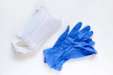 Beyaz arka planda bir çift lateks tıbbi eldiven ve cerrahi kulak ilmiği maskesi. Koruma konsepti. Coronavirus COVID-19 salgını.