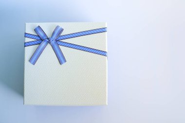 Beyaz hediye kutusunun üst görüntüsü ya da mavi kurdeleli mevcut kutu paketi ve metin için metin alanı olan mavi ve beyaz bir arkaplan üzerinde yay. Aşkın ve sürprizin sembolü.