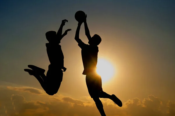 ゴールキーパーのジャンプのシルエットは日没の背景と空気中のボールをキャッチします — ストック写真