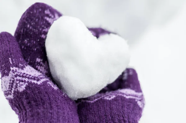 Manos femeninas en manoplas de punto cálido mantener el corazón de la nieve ag — Foto de Stock