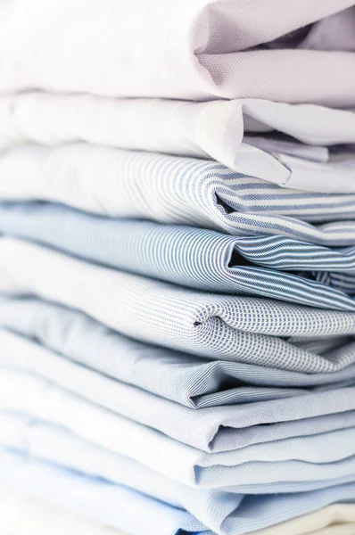 Аккуратно сложенные мужские рубашки пастельных тонов . — стоковое фото