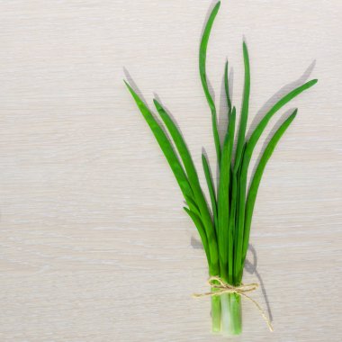 Taze yeşil soğan yaprakları bir ışık ahşap arka plan üzerinde izole buket