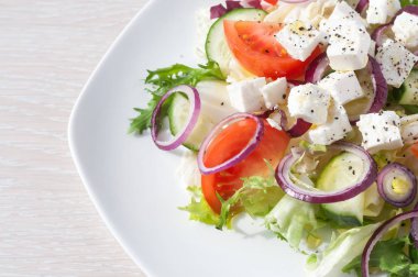 Salatalık, domates, peynir ve roka beyaz bir tabağa izole taze bahar salatası