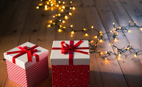 Scatole regalo rosse e luci di Natale sul pavimento in legno — Foto Stock