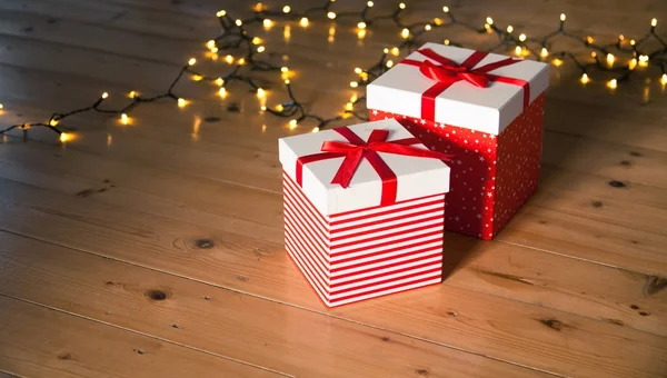 Cajas de regalo rojas y luces de Navidad en el suelo de madera —  Fotos de Stock