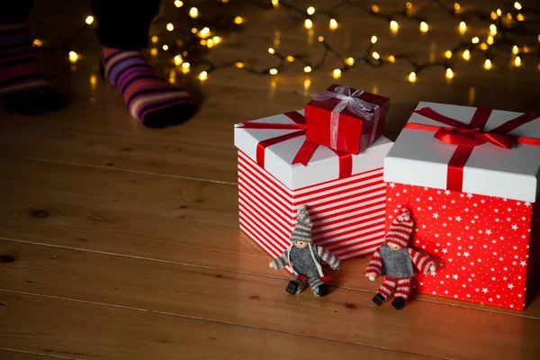 Cajas de regalo rojas pies y luces de Navidad en el suelo de madera —  Fotos de Stock