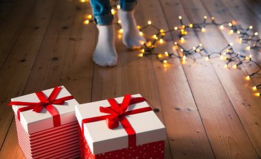 ahşap zemin üzerinde kırmızı hediye kutuları ayak ve Noel ışıkları