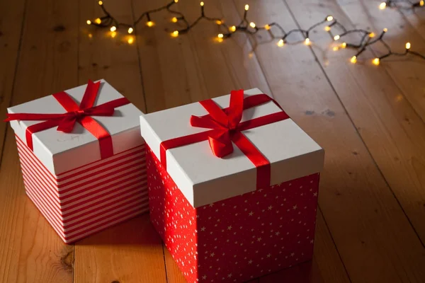 Scatole regalo rosse e luci di Natale sul pavimento in legno — Foto Stock