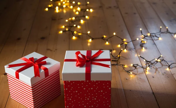 Червоні подарункові коробки та різдвяні вогні на дерев'яній підлозі — стокове фото