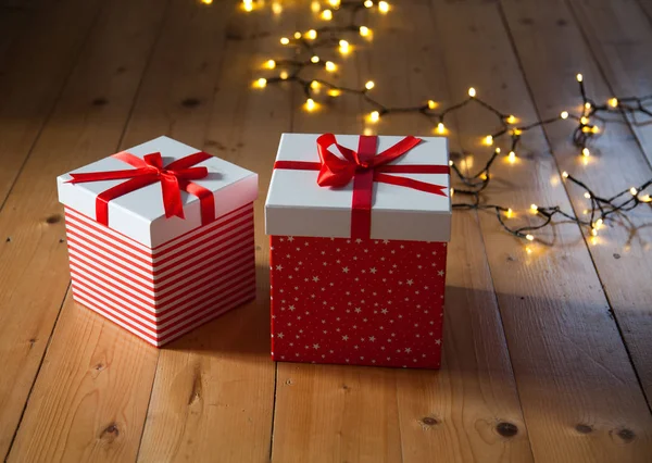 Scatole regalo rosse e luci di Natale sul pavimento in legno — Foto Stock