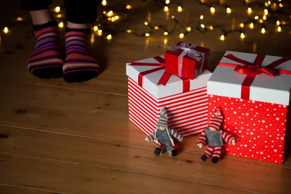 Cajas de regalo rojas pies y luces de Navidad en el suelo de madera —  Fotos de Stock