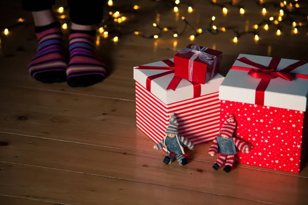 Cajas de regalo rojas pies y luces de Navidad en el suelo de madera —  Fotos de Stock