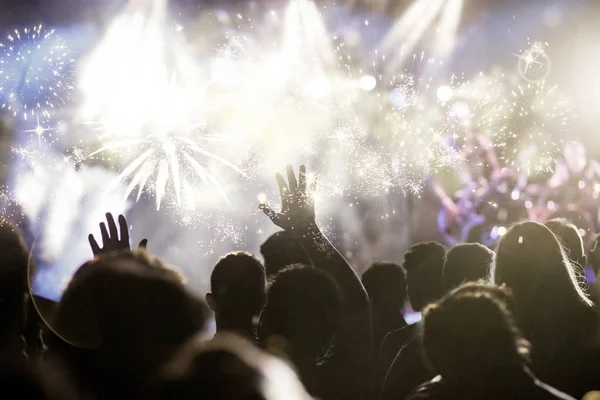 Multidão com as mãos levantadas assistindo fogos de artifício - conceito de Ano Novo — Fotografia de Stock