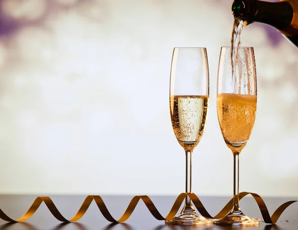 Turnarea șampaniei în pahare împotriva luminilor de vacanță — Fotografie, imagine de stoc