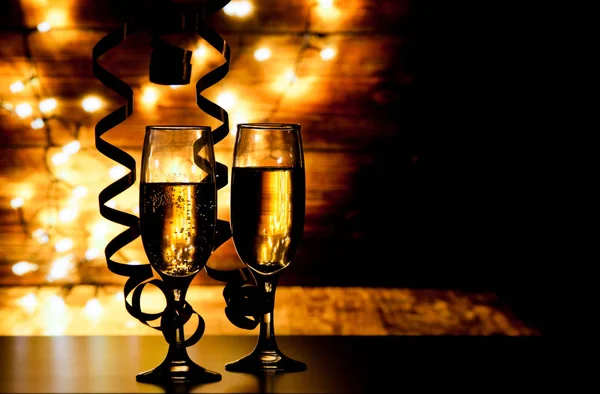 Two champagne glasses with ribbons against holiday lights and fi — Stock Photo, Image