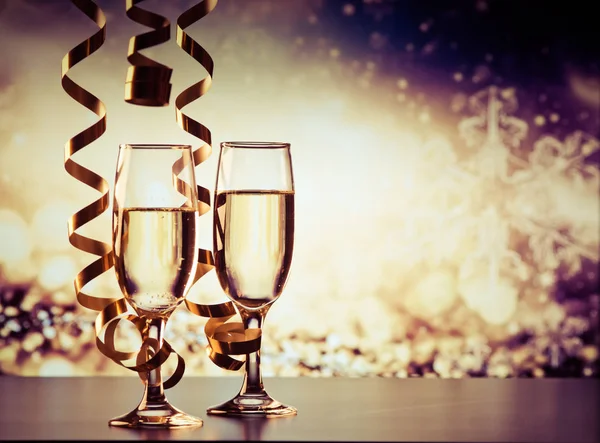 Two champagne glasses with ribbons against holiday lights and fi — Stock Photo, Image