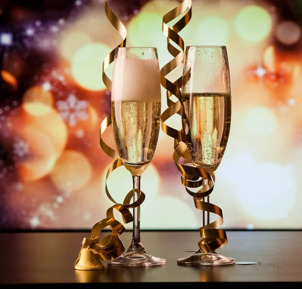 Two champagne glasses with ribbons against holiday lights and fi — Stock Photo, Image