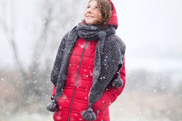 Donna in cappotto rosso che cammina in una forte nevicata in campagna — Foto Stock
