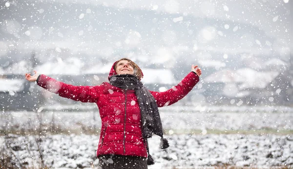 Donna in cappotto rosso che cammina in una forte nevicata in campagna — Foto Stock