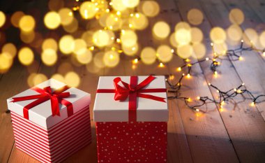 Kırmızı hediye kutuları ve ahşap zemin üzerinde Noel ışıkları