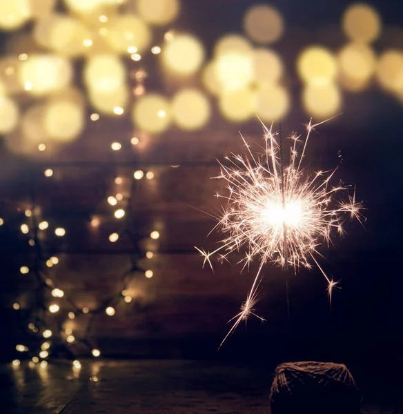 Горящие искры и рождественские огни на деревянном фоне — стоковое фото
