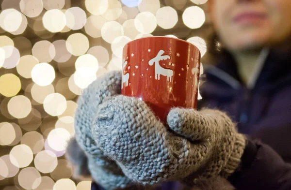 Mulher segurando caneca com vinho quente no mercado de natal — Fotografia de Stock