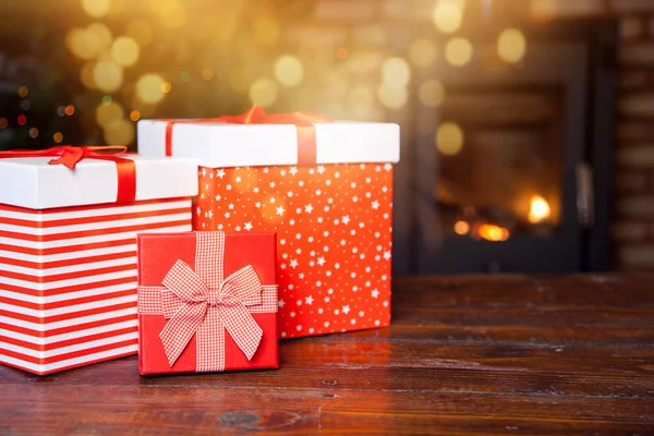 Red gift boxes and burning fireplace in the background — Stock Photo, Image