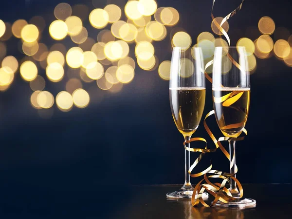 Due bicchieri di champagne con nastri contro le luci delle vacanze e fi — Foto Stock