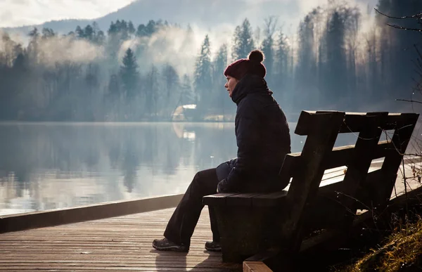 Frau sitzt auf Bank an einem nebligen Herbstmorgen am Bleder See — Stockfoto