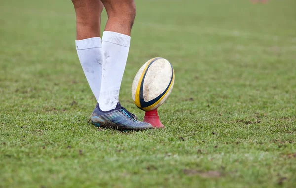 rugby player preparing to kick the oval ball during game