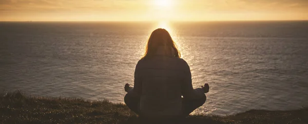 Vacker kvinna som gör yoga vid havet vid solnedgången-yoga, mindfuln — Stockfoto