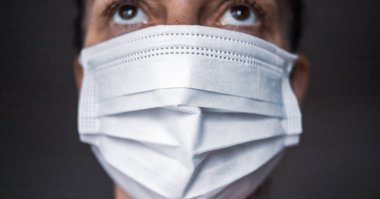  Bir kadın ağzına ve burnuna kağıt bir maske takar.