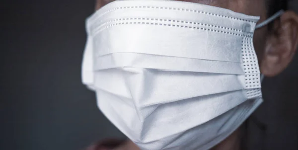 Женщина надевает бумажную маску для лица на рот и нос для защиты — стоковое фото