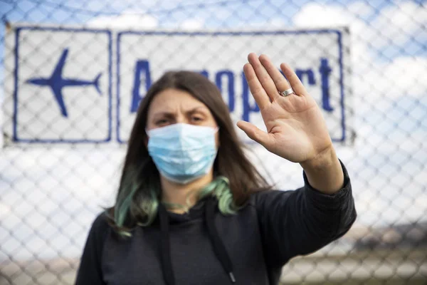 coronavirus global fight - woman wearing surgical mask and airport sign - cancelled flights - travel ban