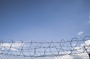 Boş açık mavi gökyüzü arkaplanındaki dikenli tel