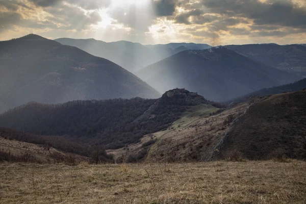 epic landscape with ruins of a castle and heavenly lights at sunset. Liteni fortress in Transylvania.