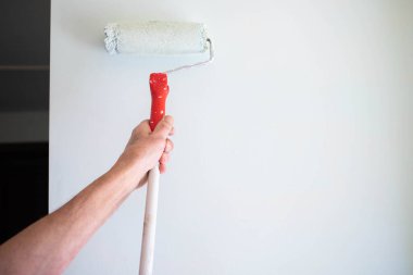 Boya silindirli erkek el boyası duvar. Daire boyama, beyaz boyayla yenileme.