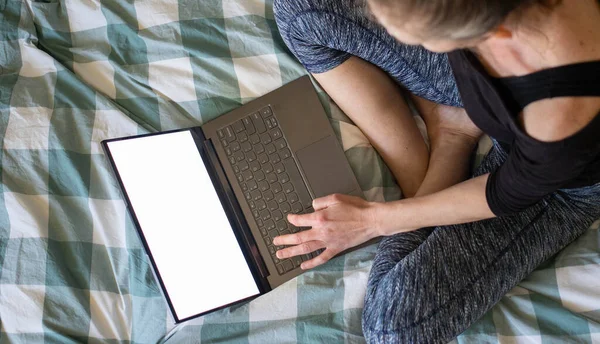 在床上使用笔记本电脑或平板电脑的妇女白屏复制空间 — 图库照片