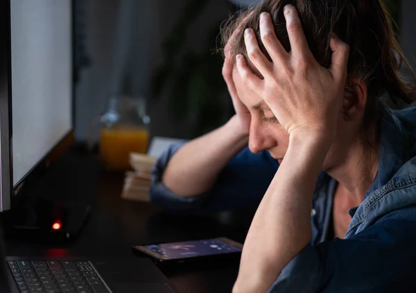 depressed woman working from home holding her head