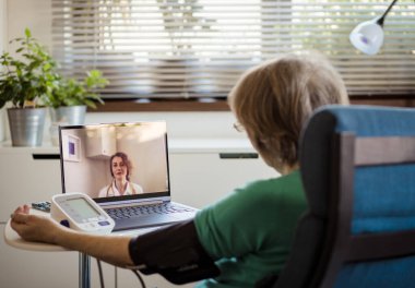 telemedicine concept elderly woman speaking to her doctor online and taking her blood pressure clipart