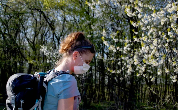 科维德19型流感大流行时 在春天的森林里独自行走的女人戴着医疗面罩 — 图库照片