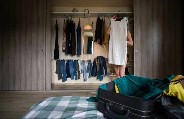 Γυναίκα Συσκευασίας Μια Βαλίτσα Δοκιμάζοντας Ρούχα Ντουλάπα Στο Παρασκήνιο — Φωτογραφία Αρχείου
