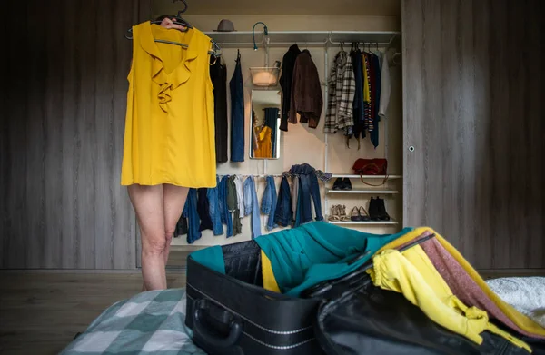 Γυναίκα Συσκευασίας Μια Βαλίτσα Δοκιμάζοντας Ρούχα Ντουλάπα Στο Παρασκήνιο — Φωτογραφία Αρχείου