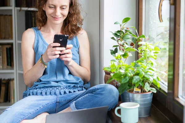 Lycklig Kvinna Använder Smartphone Hemma Genom Fönstret Sociala Medier Anslutning — Stockfoto